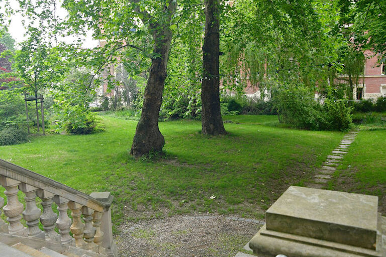 Blick von einer Treppe mit historischem Steingeländer in einen Garten mit großen alten Bäumen