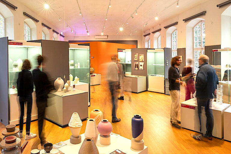 Blick in einen Ausstellungsraum der Grassimess mit Besuchern, Ständen und Vitrinen