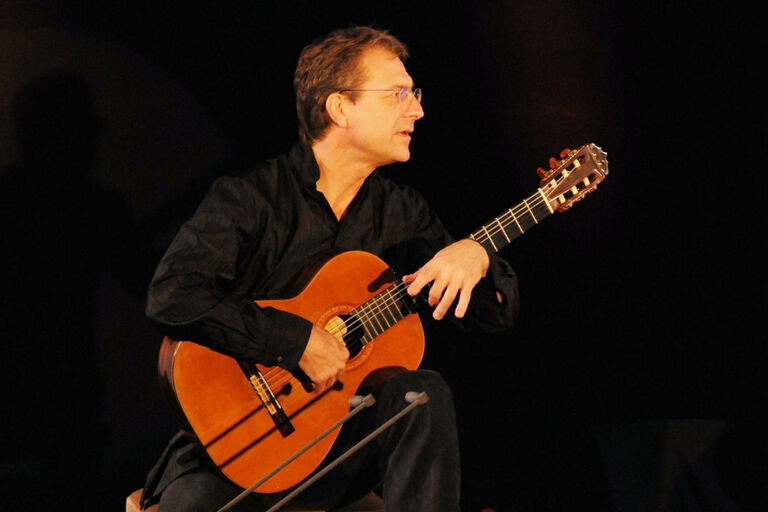 Der Musiker spielt bei einem Konzert sitzen auf seiner Gitarre.