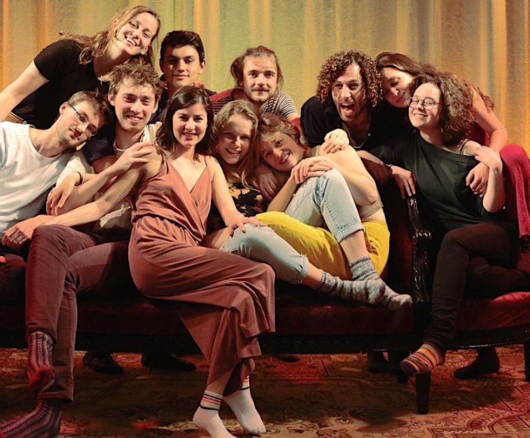 Fröhliches Gruppenfoto der elf Sängerinnen und Sänger auf einem kleinen Sofa