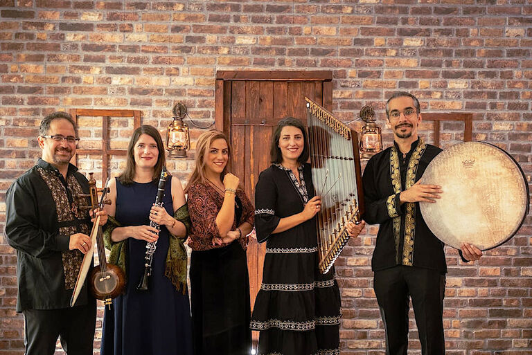 Gruppenfoto des Ensembles mit seinen Instrumenten vor einer Ziegelwand