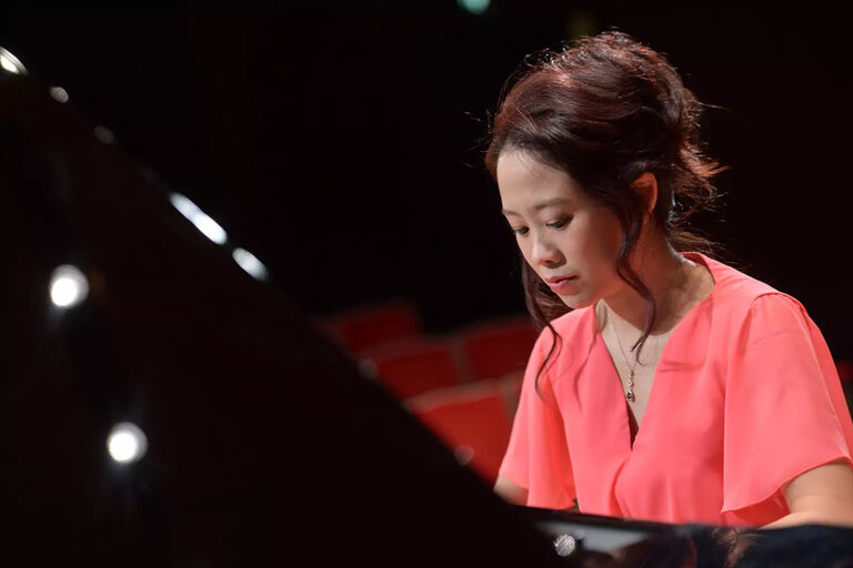 Die Pianistin spielt mit konzentriertem Gesichtsausdruck an einem Konzertflügel.