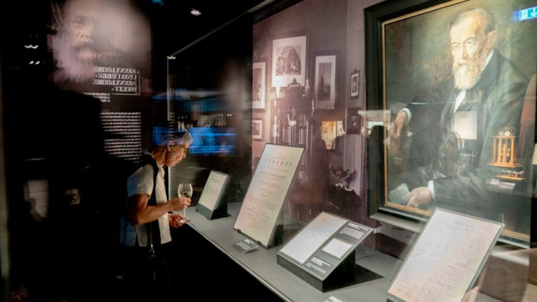 Ein Besucherin steht vor einer Vitrine mit Bildern und Schriftstücken von Wilhelm Wundt.