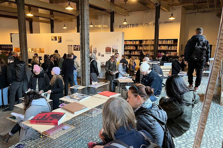 Viele Menschen in einer Halle, die sich Bücher oder Ausstellungen ansehen