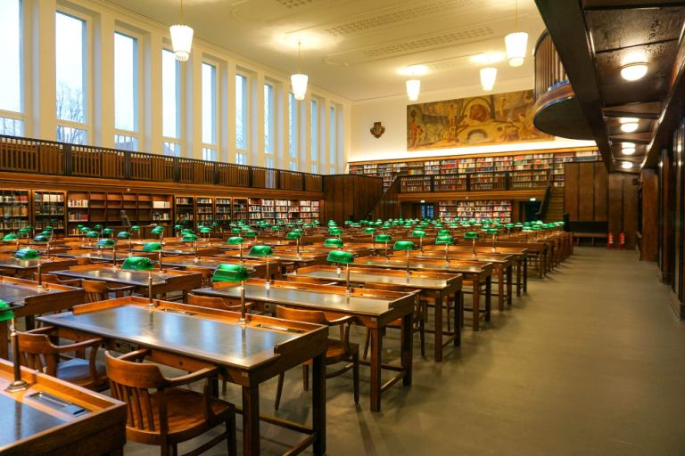 Blick in den historischen Lesesaal mit seinen originalen Holztischen und -stühlen und Bücherregalen bis zur Decke