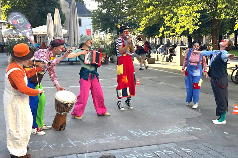 Sechs Clowns treten mit verschiedenen Instrumenten in der Leipziger Innsenstadt auf.