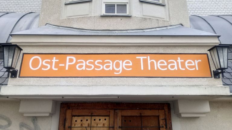 Foto des Theatereingangs mit dem markanten orangefarbenen Schild