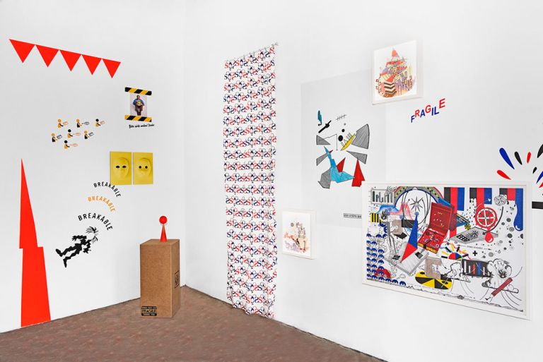 Blick in einen hellen Ausstellungsraum mit Bildern und Schriftzügen an den Wänden und einer kleinen Skulptur auf einem Sockel
