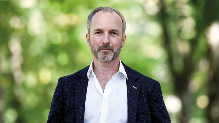 Portraitfoto von Stefan Schwarz in weißem Hemd und Sakko im Grünen