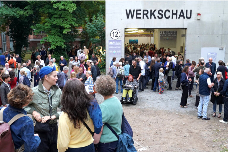 Viele Menschen befinden sich vor un in einer großen Halle mit weit geöffneten Toren