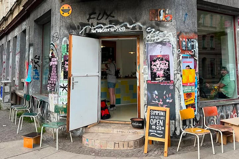 Eingang und große Schaufenster des Cafés in einem unsanierten Gründerzeit-Haus