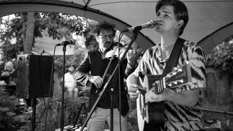 Das Duo beim Auftritt: Deen spielt Gitarre und singt, währen Blumenstein Geige spielt.