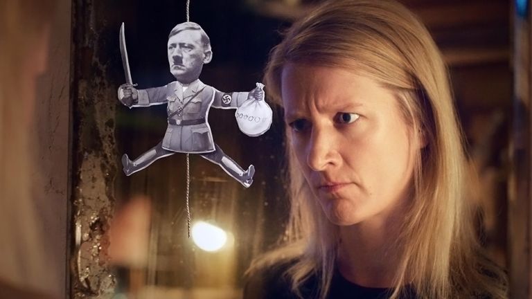 Die Protagonisten schaut auf einen Hampelmann, der vor ihr hängt und der Fotos von Adolf Hitler zusammengesetzt wurde.