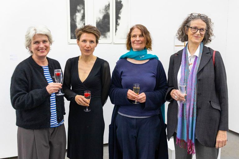 Gruppenfoto der lächelnden Künstlerinnen mit einem Glas Sekt in der Hand bei der Vernissage ihrer Ausstellung