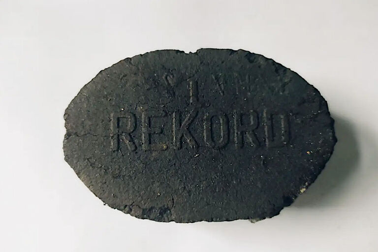 Ein ovales Kohlebrikett, auf das das Wort Rekord geprägt wurde