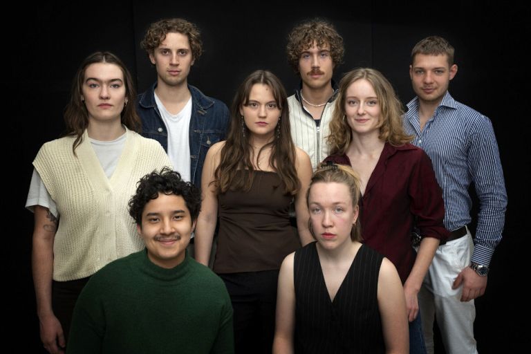 Gruppenfoto der vier Schauspielerinnen und vier Schauspieler vor einem dunklen Hintergrund