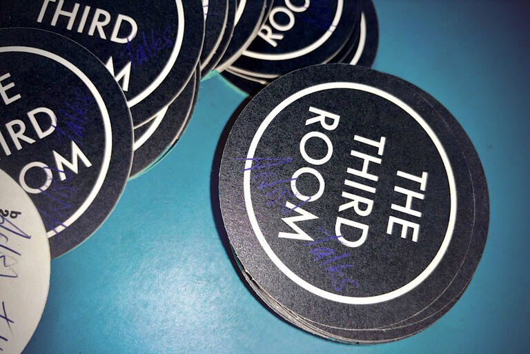 Auf einem Blauen Untergrund liegen Bierdeckel mit der Aufschrift "THE THIRD ROOM".