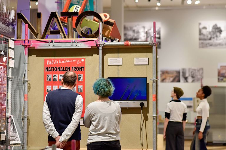 Besucherinnen und Besucher sehen sich Ausstellungsstücke in der Schau an.