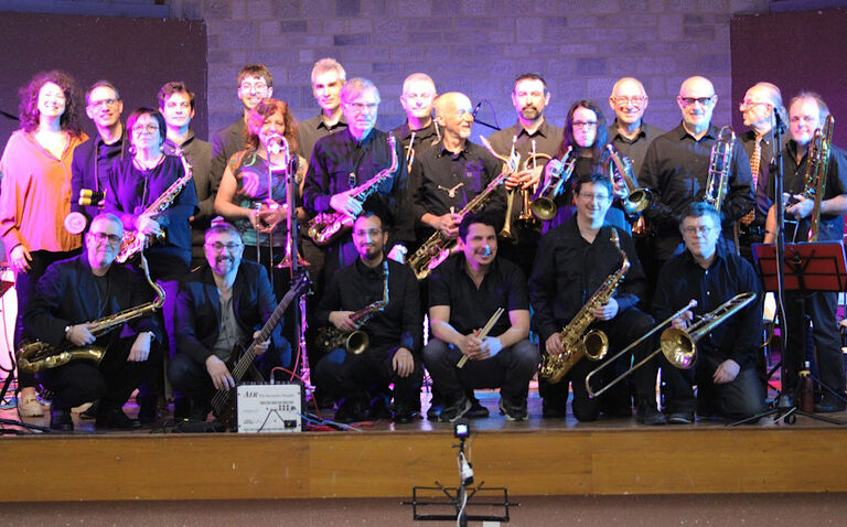 Gruppenfoto des Ensembles mit freundlich blickenden Musikerinnen und Musikern