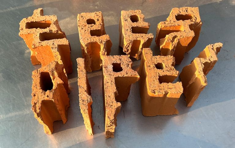 Auf einer Metallplatte liegen behauene Ziegelsteine, die die Worte "Geek Piper" ergeben.