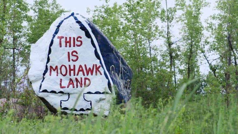 Ein großer, blau und weiß angemalter Felsbrocken trägt in rot die Aufschrift "THIS IS MOHAWK LAND".