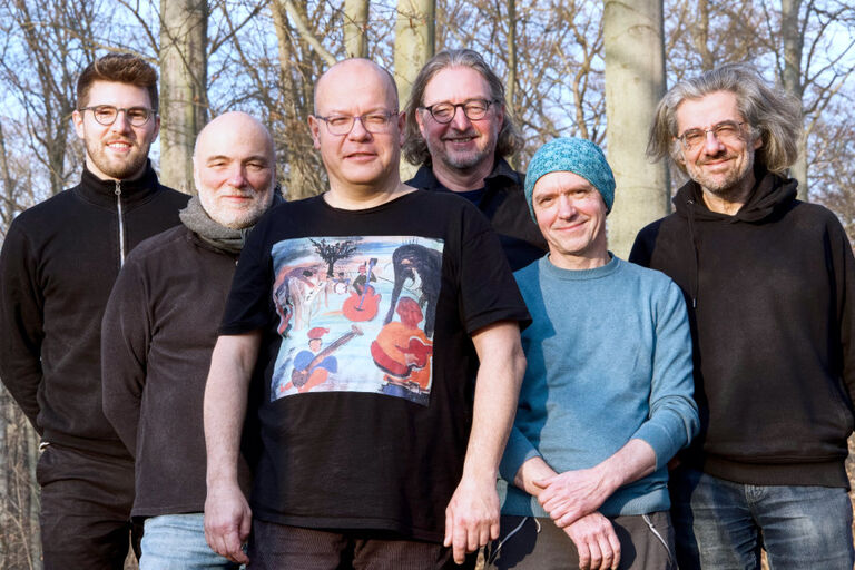 Gruppenfoto im Freien mit blätterlosen Bäumen im Hintergrund