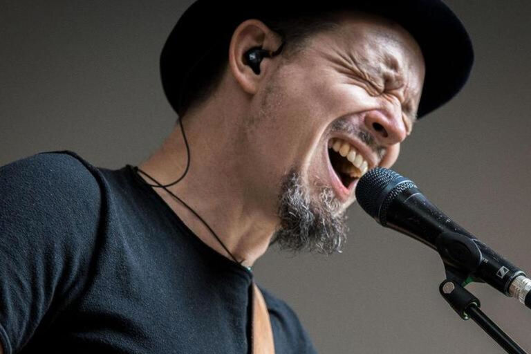 Der Künstler singt mit zusammengekniffenen Augen in ein Mikrofon.