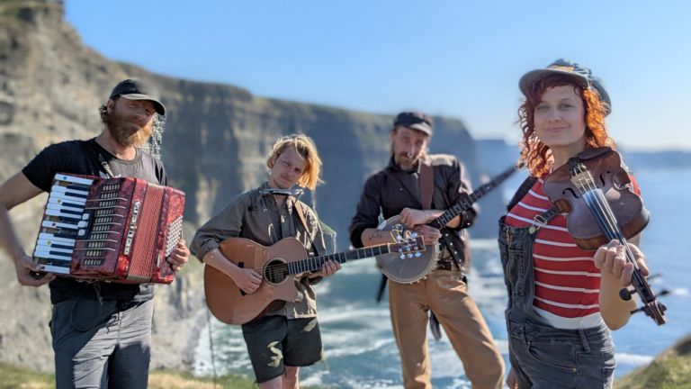 Gruppenfoto der Band vor einer Steilküste am Meer