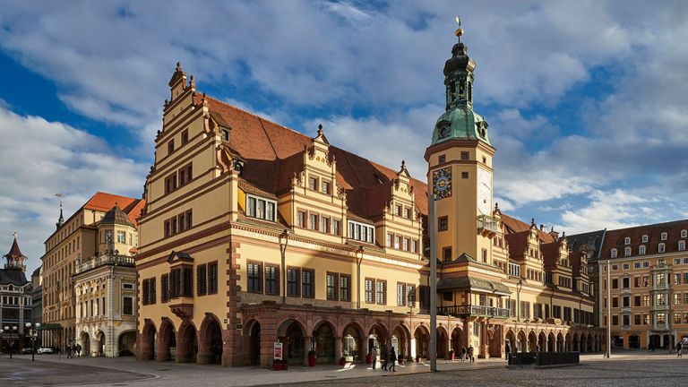 Das Alte Rathaus vom Markt aus gesehen, im Sonnenschein und vor blauem Himmel mit weißen Wolken.