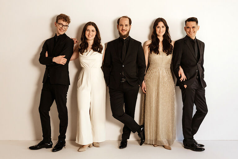 Gruppenfoto des freundlich lächelnden Ensembles in festlicher Garderobe