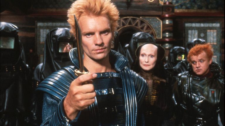 Filmszene mit Sting im futuristischen Kostüm, der ein Messer in der Hand hält