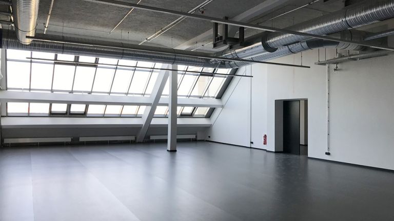 Blick ein einen großen hellen Proberaum mit verglaster Wand
