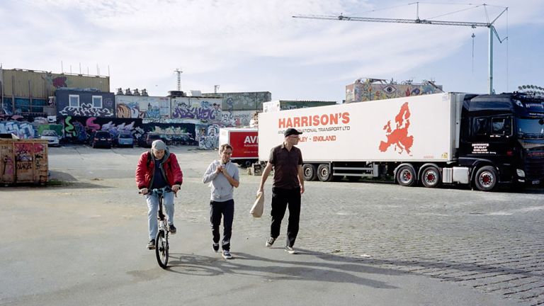 Foto der drei Musiker, die auf einem großen Gewerbehof unterwegs sind