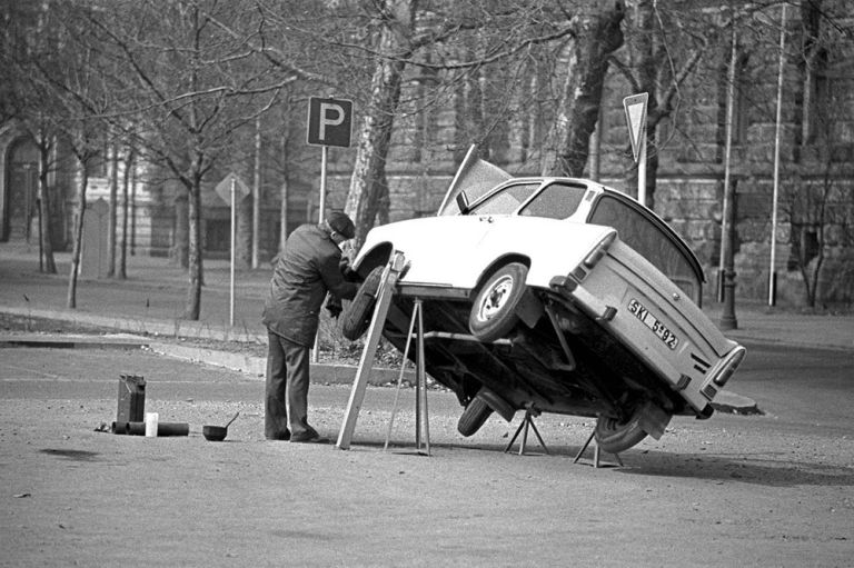 Historisches Foto eines Mannes, der an seinem aufgebockten Trabant werkelt