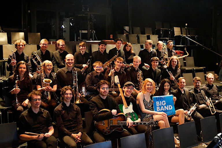 Gruppenfoto der fröhlichen Musikerinnen und Musiker auf der Bühne