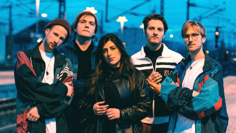 Foto der Band auf einem nächtlichen Bahnsteig
