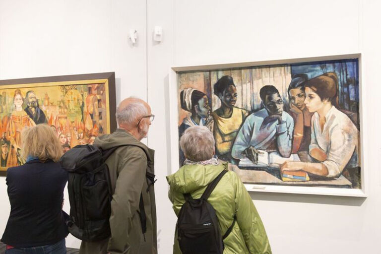 Besucher einer ausstellung stehen vor zwei Gemälden