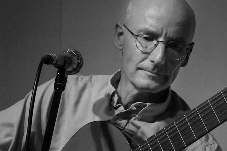 Der Musiker und Sänger spielt mit konzentriertem Gesichtausdruck Gitarre.