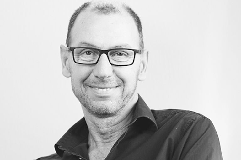 Schwarz-Weiß-Foto des lächelnden Künstlers mit Hornbrille