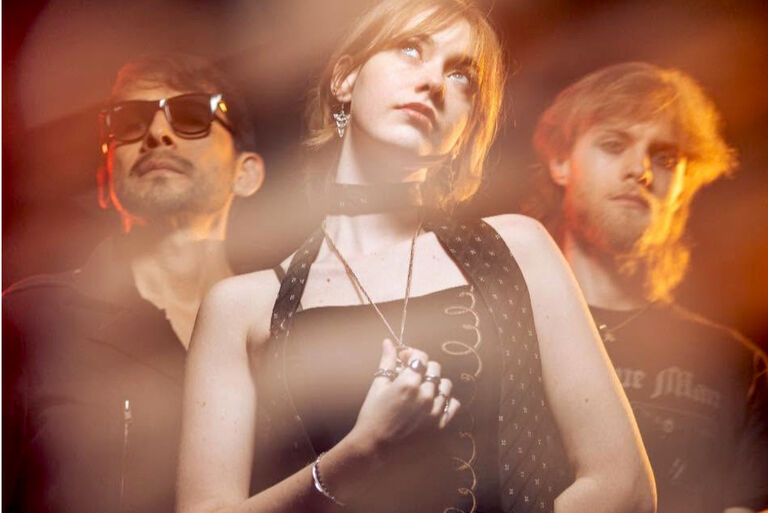 Leicht verwischtes Bandfoto, auf dem die Sängerin und die neiden Musiker verträumt in die Ferne schauen