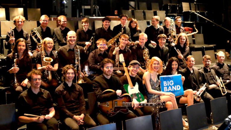 Gruppenfoto der fröhlichen Musikerinnen und Musiker auf der Bühne