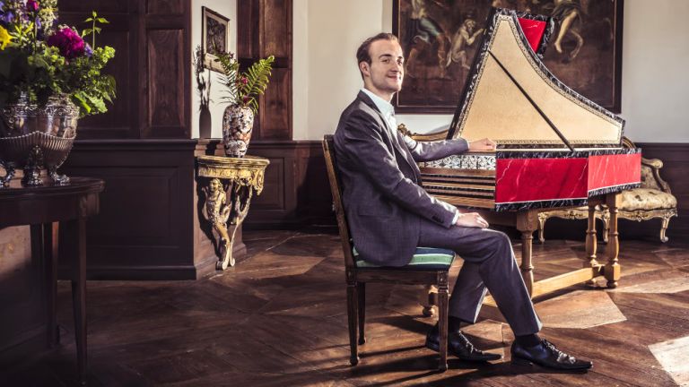 Alexander von Heißen sitzt in einem Salon lächelnd an einem Cembalo.
