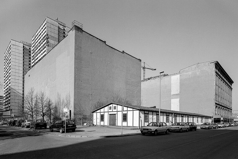 Stadtansicht, mit großen Baulücken zwischen einzelnen Gründerzeithäusern und riesigen Plattenbauten im Hintergrund