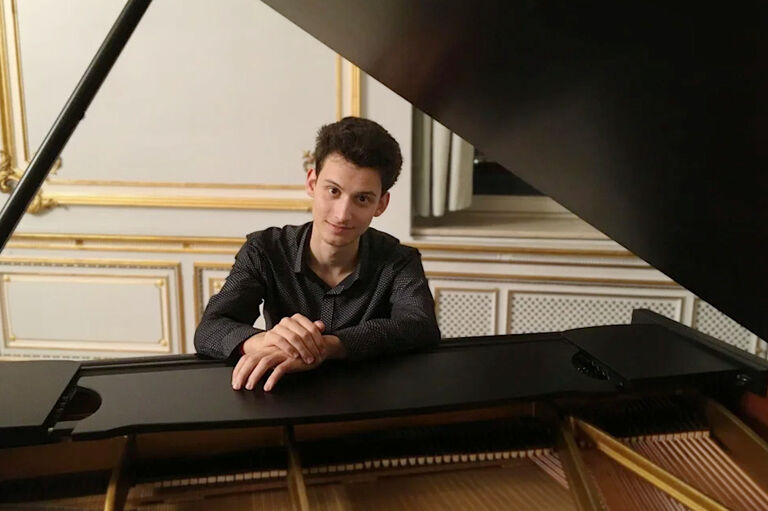 Der Pianist sitzt lächelnd an seinem Flügel