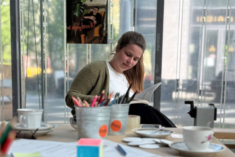 Eine junge Frau sitzt lesend an einem Tisch im Museumscafé.