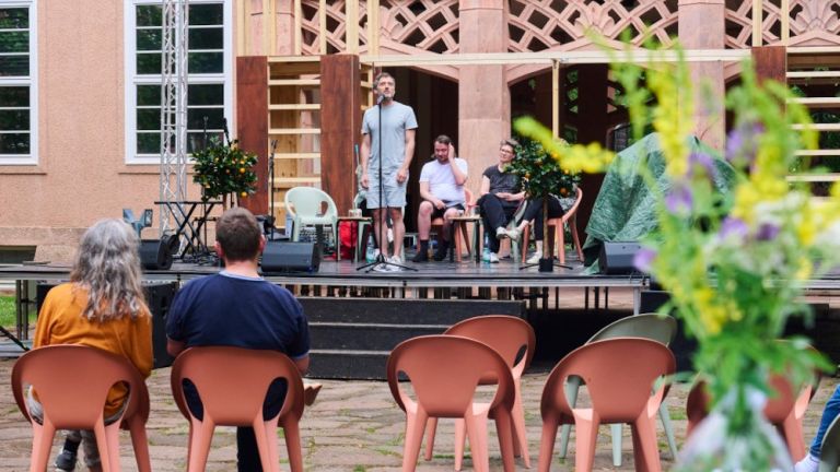 Beim Poetry Slam im Innenhof treten die Teilnehmer auf einer niedrigen Bühne auf.