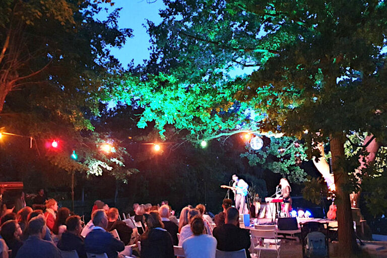 Nächtliches Konzert im Freien unter einem Baum mit bunten Lichtern