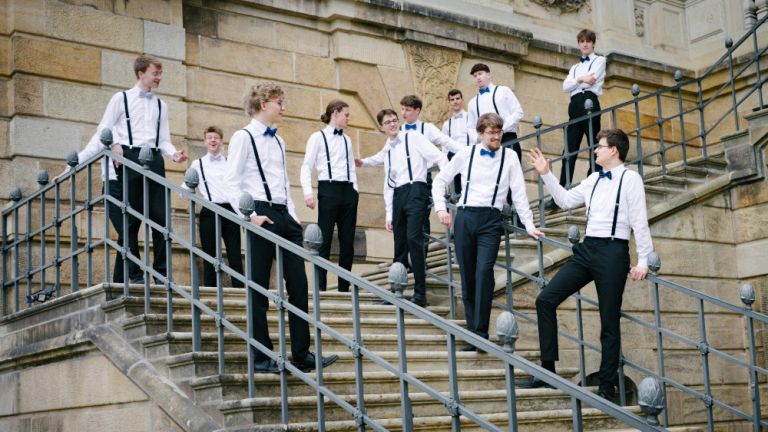 Lockeres Gruppenfoto der jungen Sänger, die auf einer historischen Treppe stehen und sich unterhalten