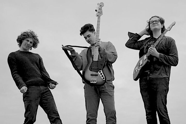 Schwarz-Weiß-Foto der drei Musiker mit ihren Instrumenten im Freien gegen den Himmel fotografiert