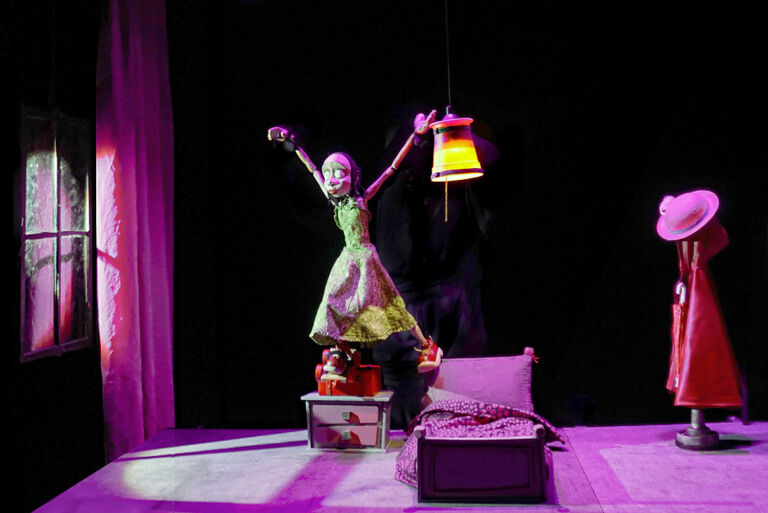 Eine Puppentheaterszene mit einem Mädchen, das nachts in ihrem Zimmer mit einer Laterne im Bett steht